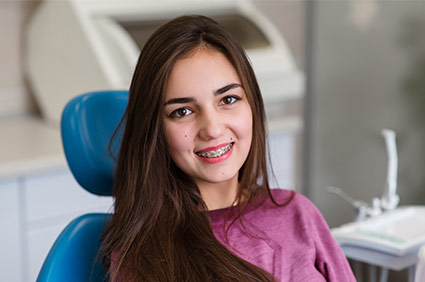 Teen female patient with braces smiling in patient chair