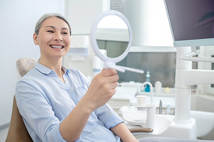 Female patient smiling and looking at her teeth at the dentist's office