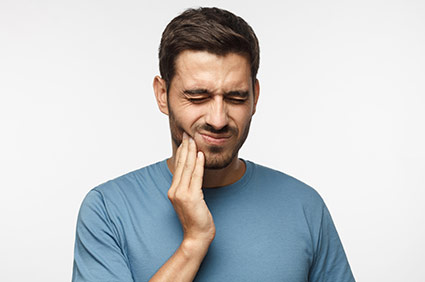 Male patient touching his cheek experiencing tooth pain